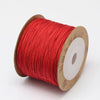 A spool of red nylon cord for jewelry making and crafting is shown on a white background.