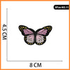 A butterfly and rose embroidered iron-on patch with pink, black, and yellow details.