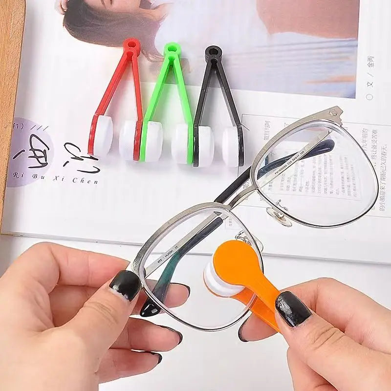 A hand holds a pair of eyeglasses, demonstrating a portable microfiber cleaning cloth with a brush and various colored cleani