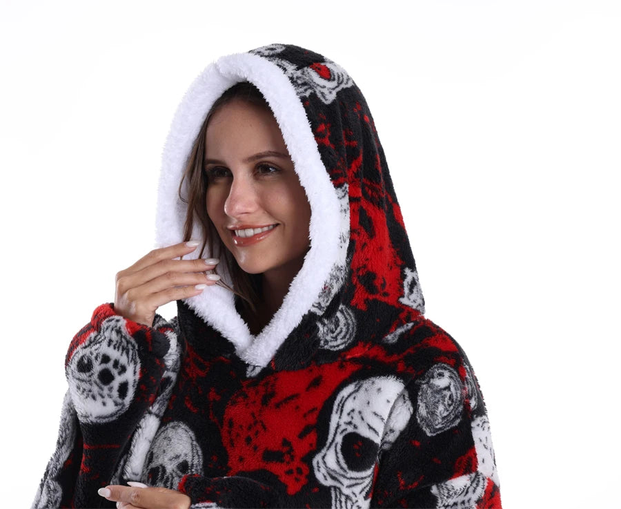 Eine lächelnde Frau trägt einen oversized Fleece-Hoodie mit schwarzem und rotem Patchwork-Totenkopfmuster und weißer Sherpa-F