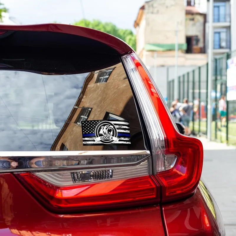 Rear view of a red car with an American flag decal on the trunk, parked outdoors.