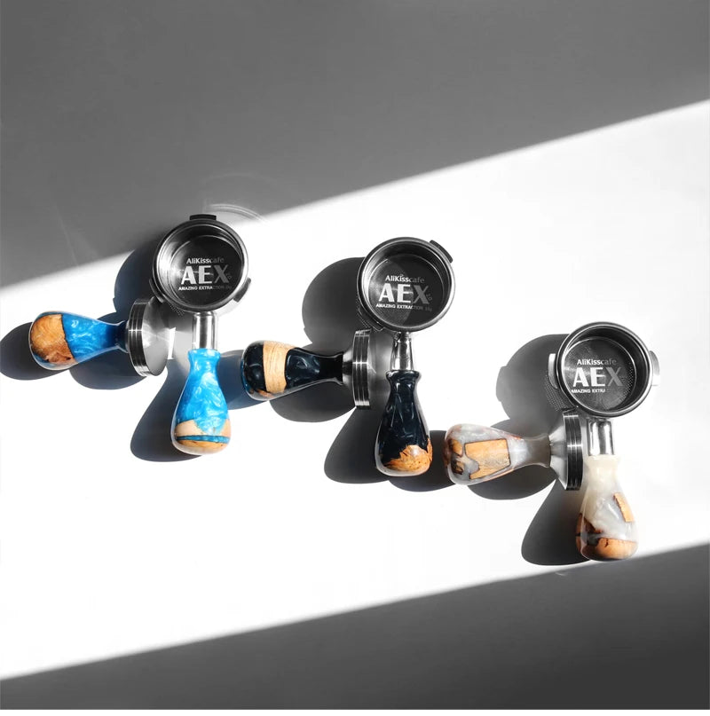 A set of three stainless steel bottomless espresso portafilters with wooden handles and AEX branding.