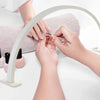 Hands are using a half-moon LED arc desk lamp to perform nail art or lash extensions.