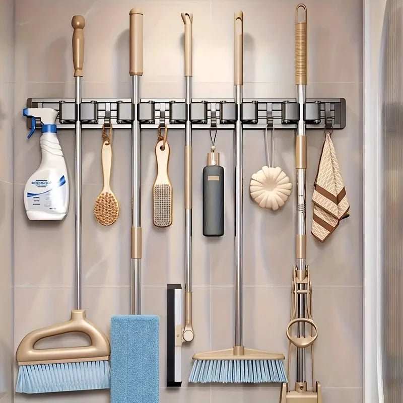 Wall-mounted metal holder displaying various cleaning tools including mops, brooms, and scrubbers.