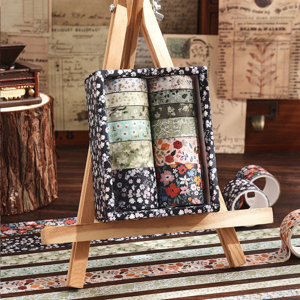Holz-Easel hält eine Box Vintage-Blumendekor-Klebeband in einem Holzrahmen vor rustikalem Hintergrund.