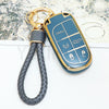 A blue TPU car key fob cover with a gold chain attached, resting on a piece of paper.