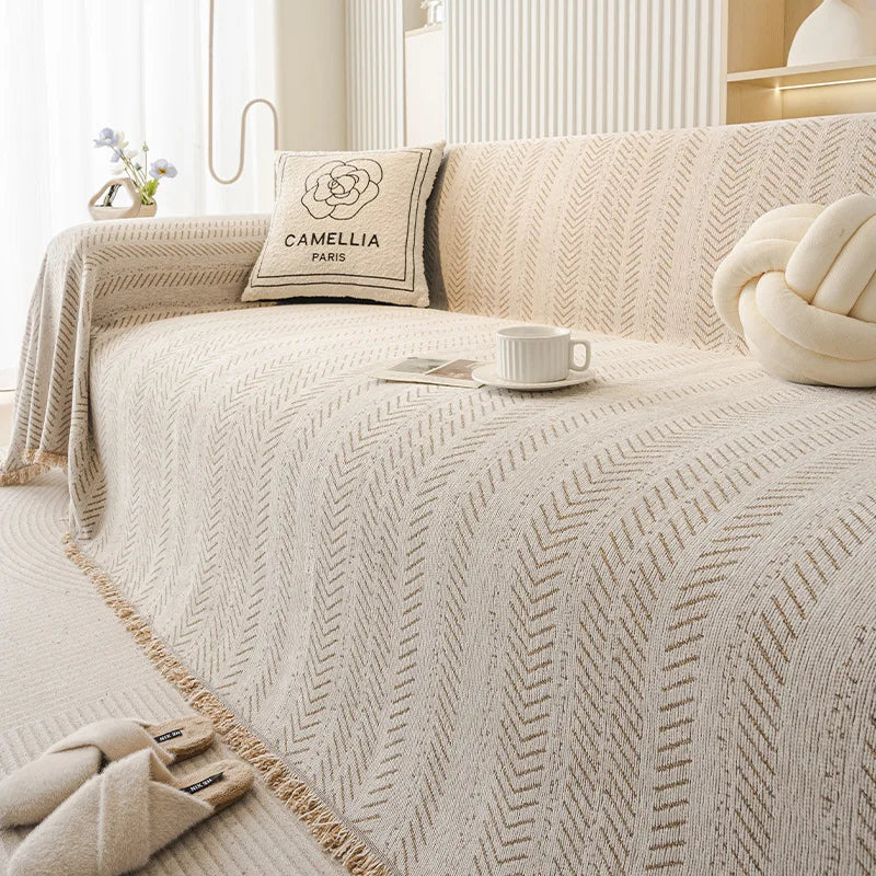 Beige Sofabezug mit eleganter Fischgrätenmuster und cremefarbener Akzentkissen.