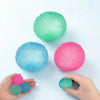 Hands hold various colored soft textured stress balls including green, blue, and pink.