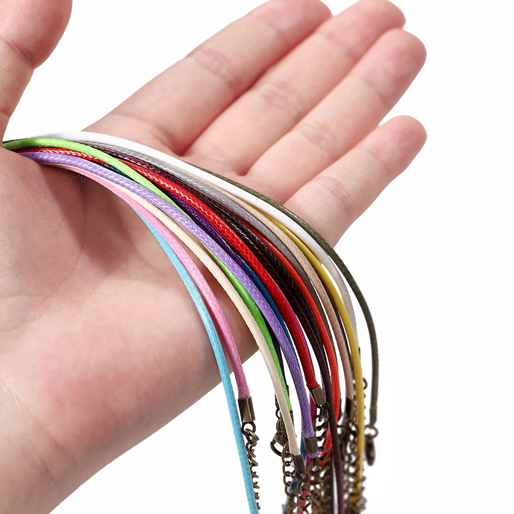 A hand holds a variety of colorful leather cords and necklaces with metal clasps.