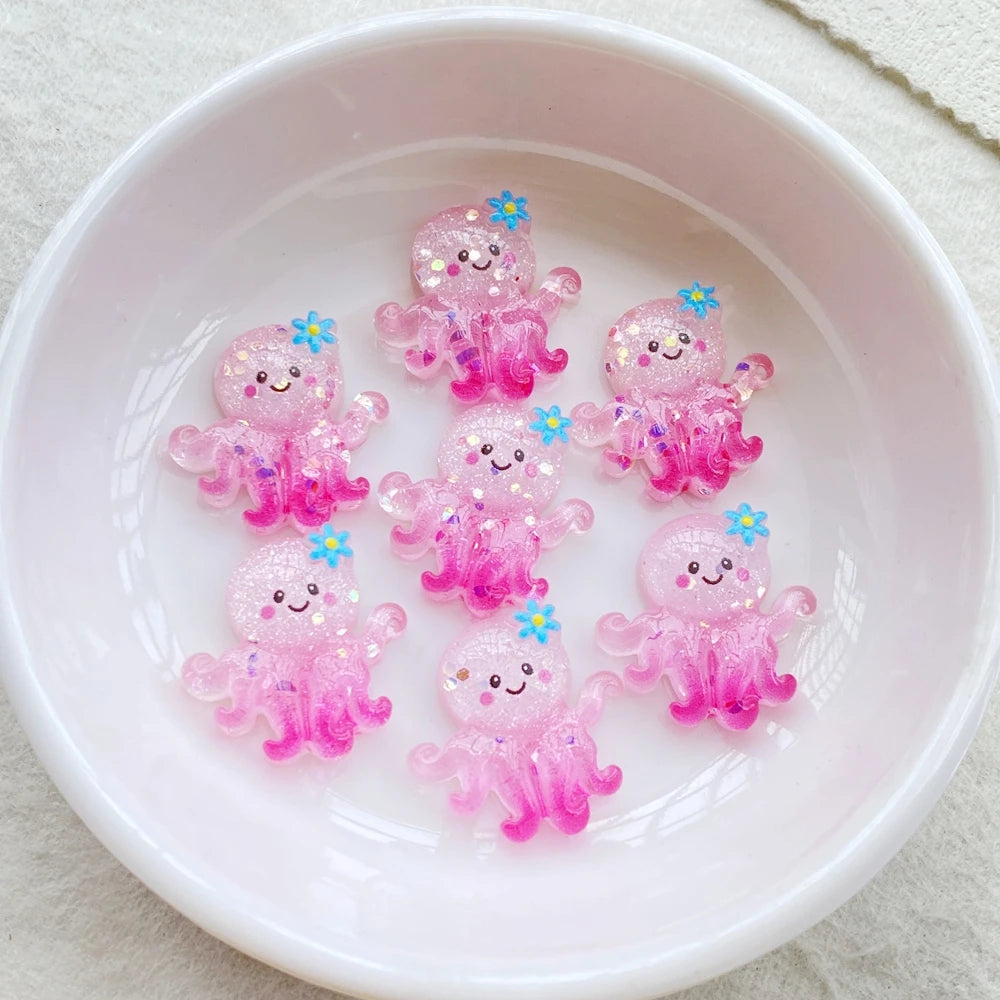 A collection of pink and purple resin charms shaped like cute, sparkling sea creatures in a white bowl.