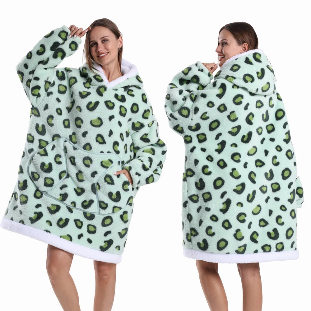 Eine Frau modelliert einen oversized Fleece-Hoodie mit grünem Leopardenmuster.