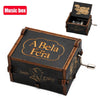 A vintage hand-crank wooden music box with a dark wood finish and gold lettering, shown next to its lid.