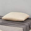 A cream-colored luxury goose down and feather pillow with a light beige cotton cover resting on a gray fabric.