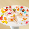 A collection of wooden pretend play cutting fruit and vegetable toys arranged on a white plate.