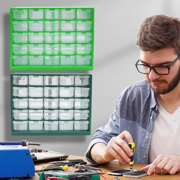 A man is working on a wooden table with a green wall-mounted parts organizer and various tools.
