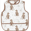 A beige waterproof baby feeding bib with a sleeveless design featuring a repeating pattern of small birds.
