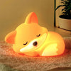 A glowing orange fox night light resting on a textured surface.