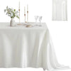 A white satin tablecloth set for dining featuring tall candles, glassware, and a floral centerpiece.