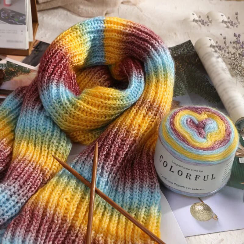 A close-up of colorful gradient cake yarn in various shades of purple, blue, yellow, and orange, displayed for knitting or cr