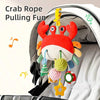 A crab rope pulling fun toy with red and orange claws and hanging colorful rattles inside a baby carrier.