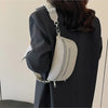 A woman is holding a light beige multi-pocket PU leather waist bag with an adjustable strap against a dark blazer.