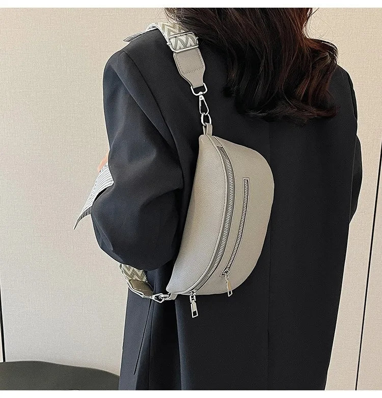 A woman is holding a light beige multi-pocket PU leather waist bag with an adjustable strap against a dark blazer.
