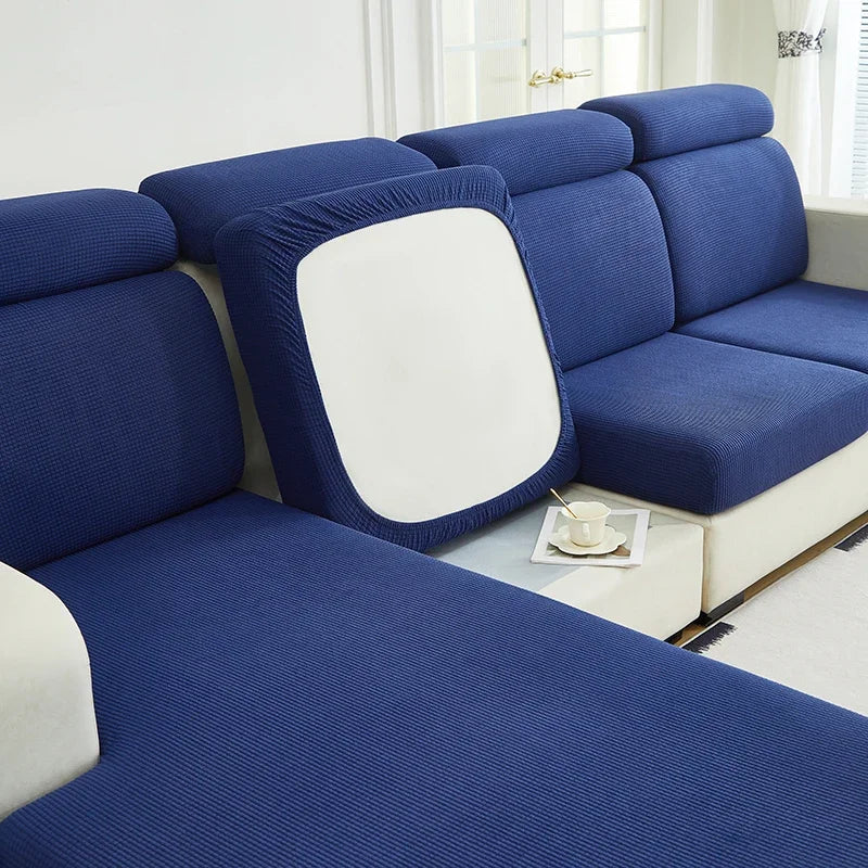 A deep blue Jacquard stretch sofa slipcover with white accents and non-slip grip.