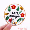 An embroidered patch featuring a red flower and green leaves on a white background.