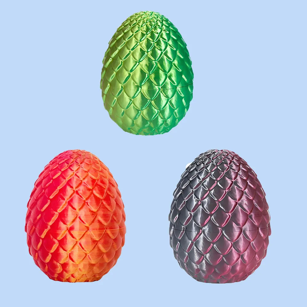 Three 3D printed dragon egg figurines in green, red, and dark gray on a light blue background.