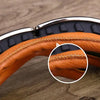 Close-up of an orange leather retro foldable motorcycle goggle with a silver frame and black padding.