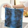 A blue microfiber cleaning cloth is being rinsed under a faucet in a kitchen sink.