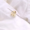 A close-up view of a sewing needle with a small, light-colored, patterned eye being threaded onto white fabric.