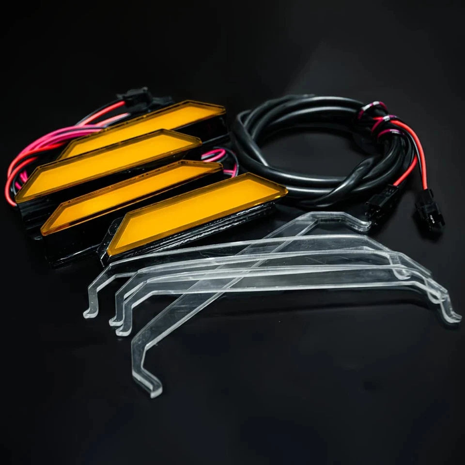 Amber LED grille lights for Ford Ranger Raptor featuring yellow light bars and clear plastic mounting brackets.