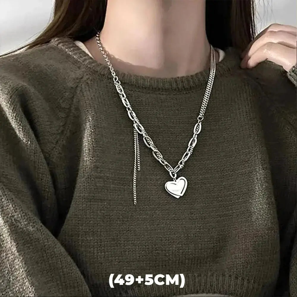 A close-up of a silver double-layer star pendant necklace worn around the neck against a dark green sweater.