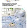 A light blue quilted blanket with a floral pattern is displayed on a bed, emphasizing gentle and cute healing life.