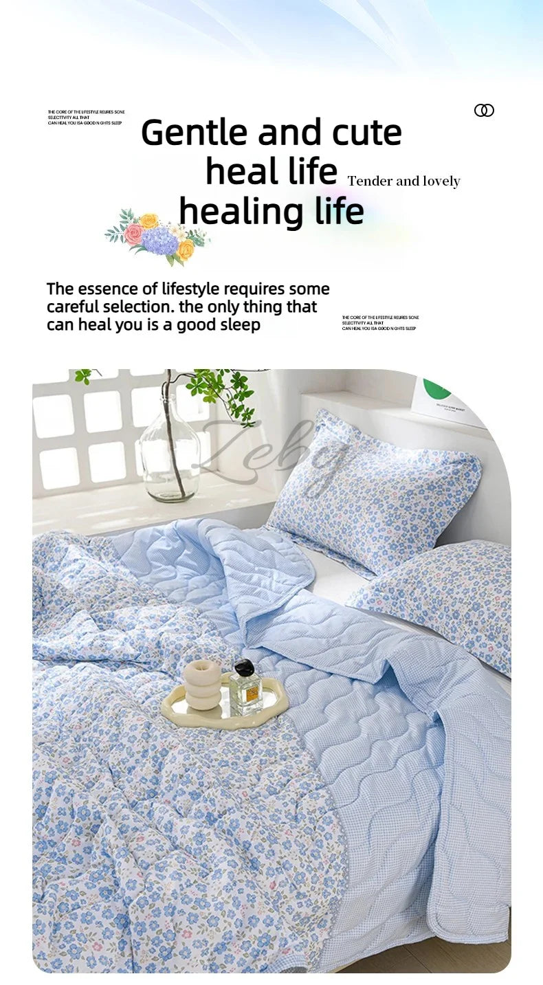 A light blue quilted blanket with a floral pattern is displayed on a bed, emphasizing gentle and cute healing life.