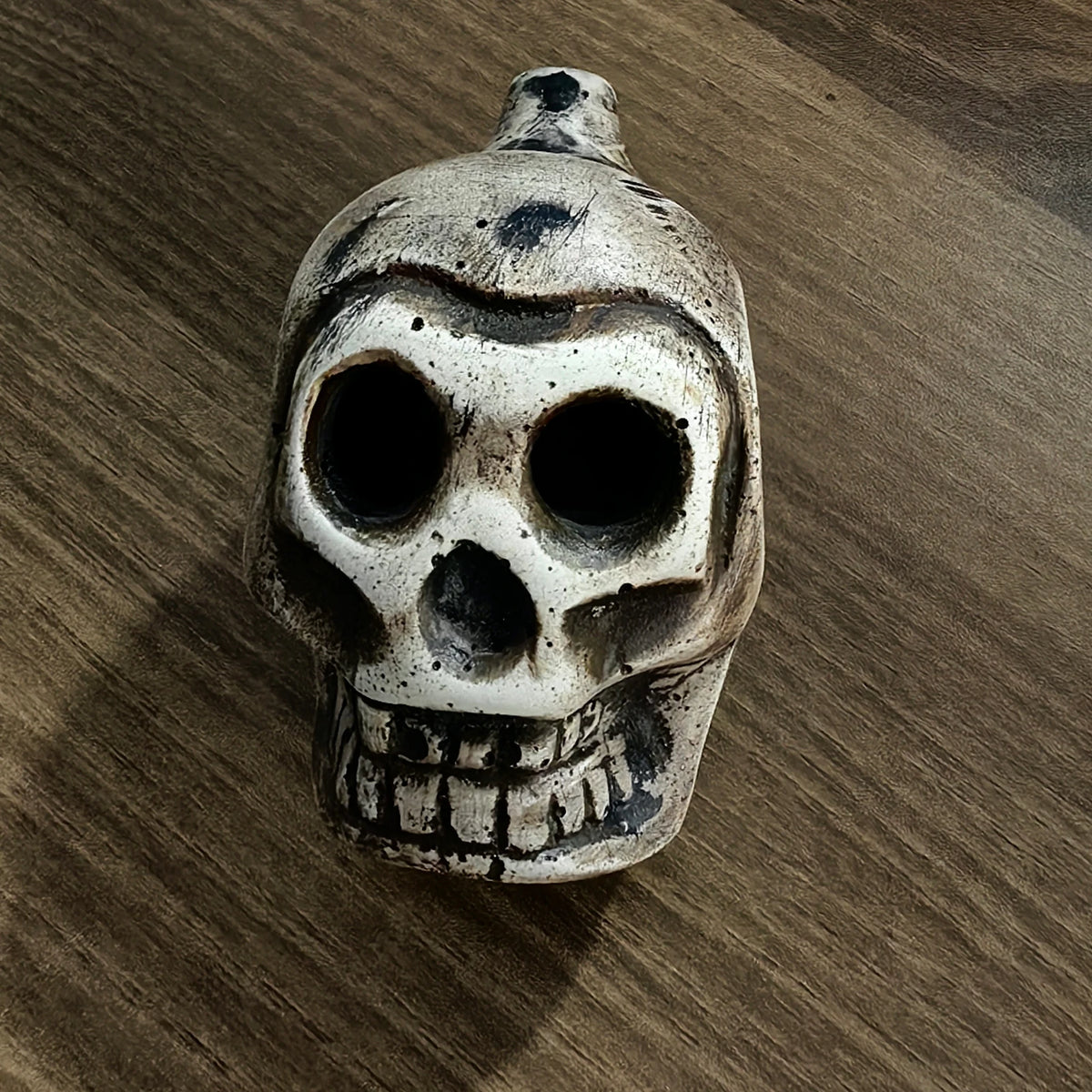 A weathered, skull-shaped object with an eerie design, possibly an Aztec death whistle.