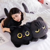 A woman is cuddling a soft black cat plush toy on a white bed.