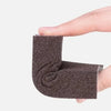 A hand holds a dark gray Emery cleaning sponge, showing its textured surface.