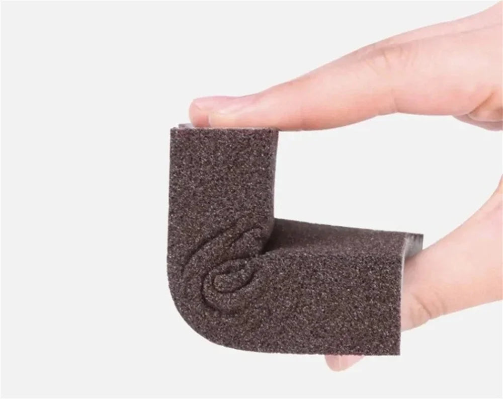 A hand holds a dark gray Emery cleaning sponge, showing its textured surface.