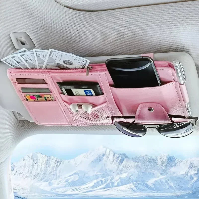 Pink car sun visor organizer holding sunglasses, a smartphone, and cash in multiple pockets.