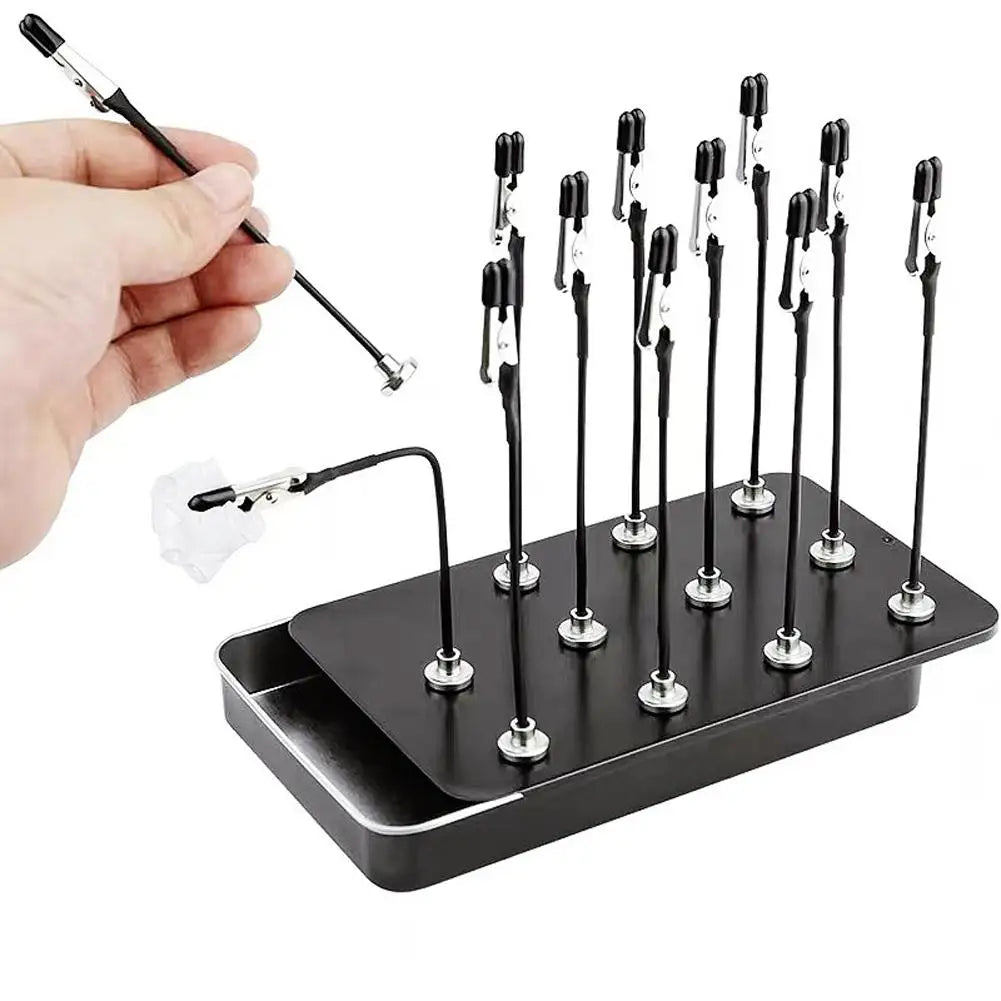 A hand holds a magnetic helping hands tool with a flexible gooseneck arm and alligator clip, positioned above a black tray of