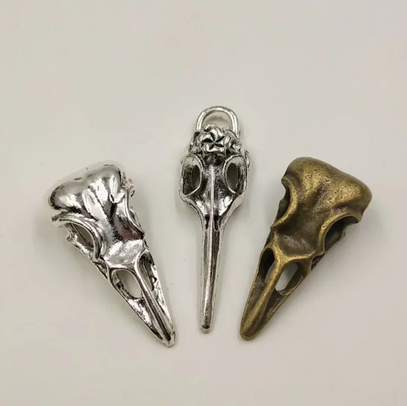 A set of five silver and brass gothic skull and crow head charms for jewelry making