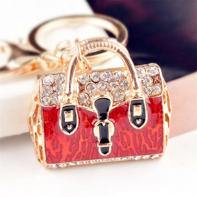 Gold-toned crystal rhinestone handbag keychain with a red leopard print detail.