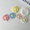 A collection of silicone daisy molds in various pastel colors including yellow, blue, pink, and cream.