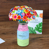 A colorful craft kit featuring felt flowers and buttons arranged in a bouquet, displayed next to a sign that reads Hello Summ