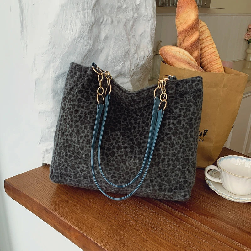 Sac en toile de léopard gris foncé avec bordure bleue, posé sur une surface en bois.