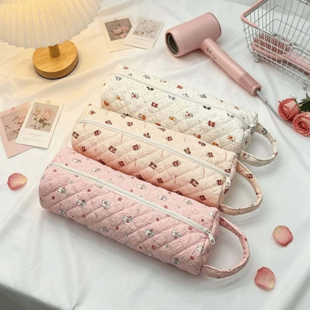 Pink and white quilted cotton storage bags with handles and a pink hair dryer are displayed on a white cloth.