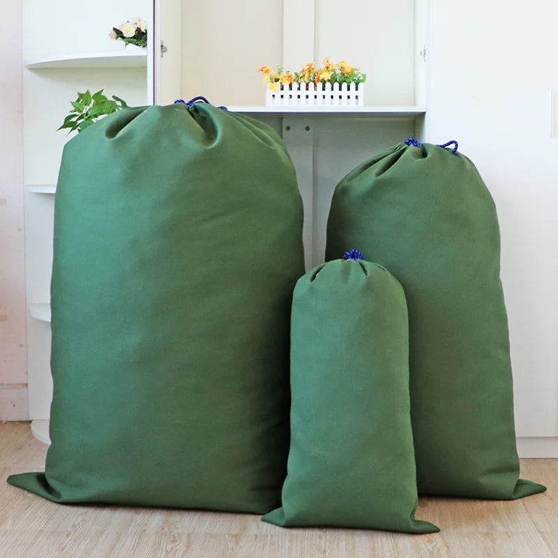 A large, olive green heavy-duty canvas laundry bag with a drawstring closure is displayed on a light wooden floor.