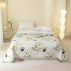 A white quilted bedspread featuring a floral pattern and black panda designs on a light-colored bed.